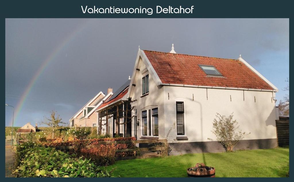 een groot wit huis met een regenboog op de achtergrond bij Vakantiewoning Deltahof in Ellewoutsdijk