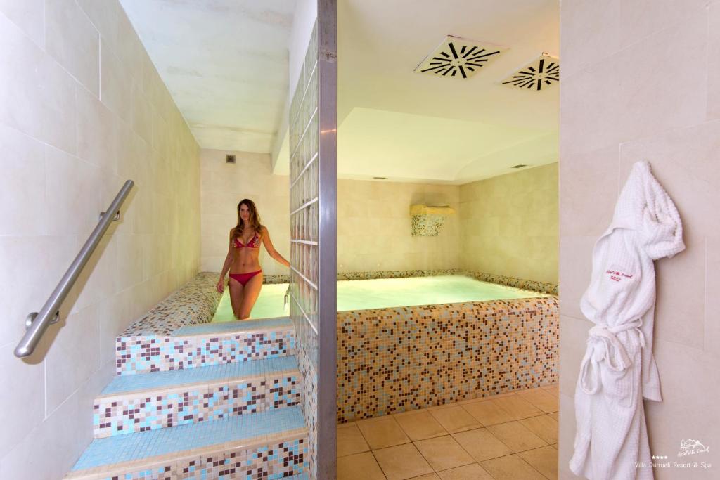 a woman is standing in a tub in a bathroom at Hotel Villa Durrueli Resort & Spa in Ischia
