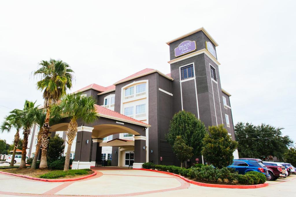 a hotel with a clock tower in a parking lot at Palacio Royale Inn Signature Katy in Katy