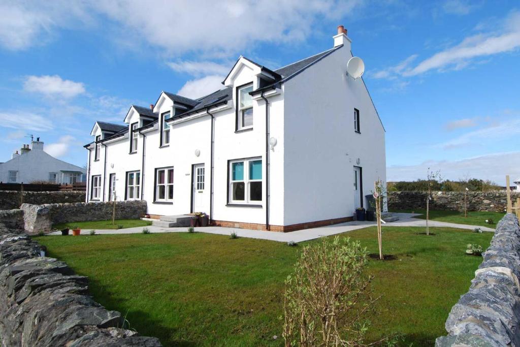 una casa bianca con un muro di pietra davanti di Sanaigmore Cottage a Port Charlotte