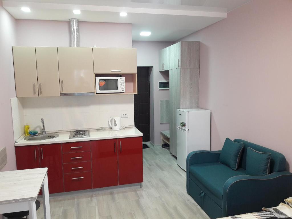 a kitchen with red cabinets and a blue chair in a room at Apartments near Metalist Stadium in Kharkiv