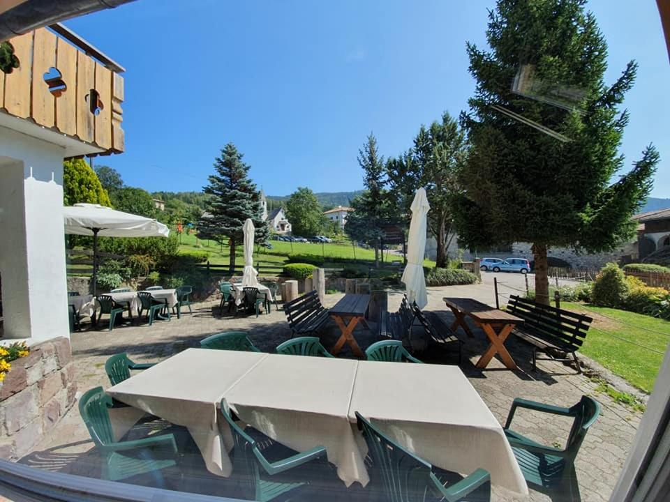 un patio con mesa, sillas y sombrillas en Albergo GARNI' AURORA, en Tret