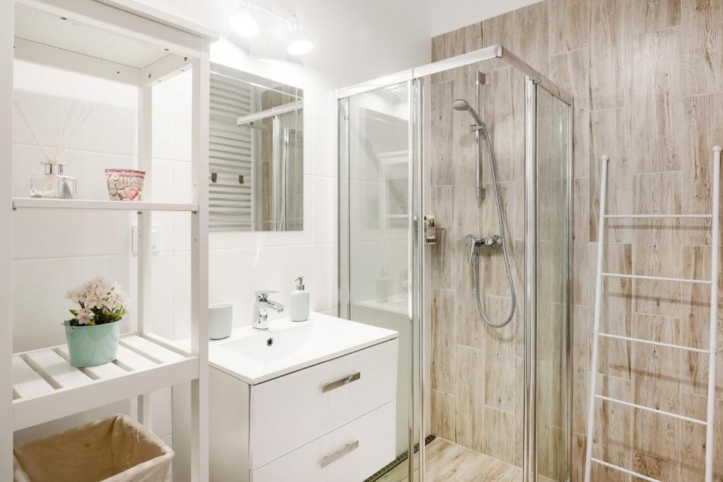 biała łazienka z prysznicem i umywalką w obiekcie M&R Apartament Airport&Business Premium Komputerowa - underground garage - free WiFi - Netflix - self check-in - 5 min from Chopin Airport w Warszawie