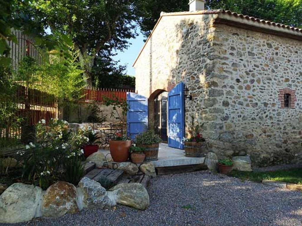 un bâtiment en pierre avec des portes bleues et des plantes en pot dans l'établissement La Grange at Laroque, à Laroque-des-Albères