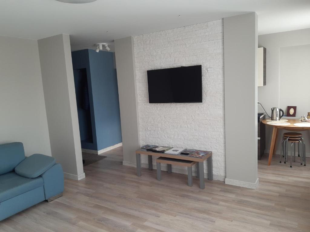 uma sala de estar com um sofá e uma televisão na parede em Atbrīvošanas aleja 80 em Rēzekne