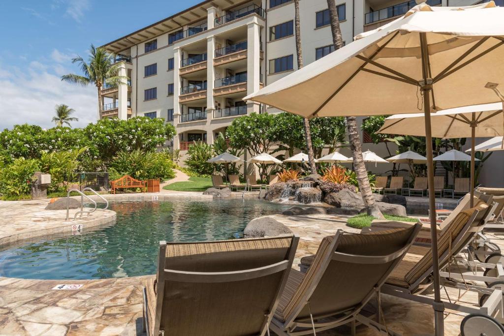 una piscina con sillas y una sombrilla y un hotel en Wailea Beach Villas, en Wailea