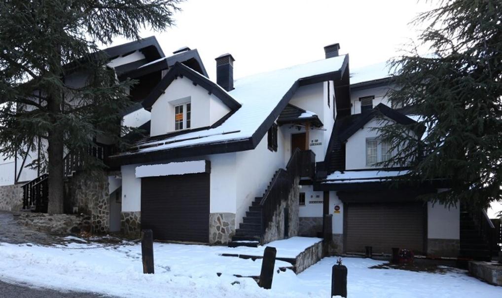 Biały dom z śniegiem na dachu w obiekcie Chalet Adosado zona med/baja w mieście Sierra Nevada