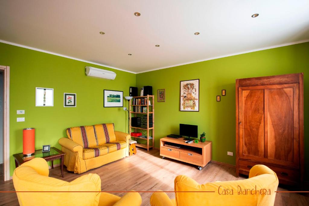 uma sala de estar com paredes verdes e mobiliário amarelo em Casa Bianchera em Monfalcone