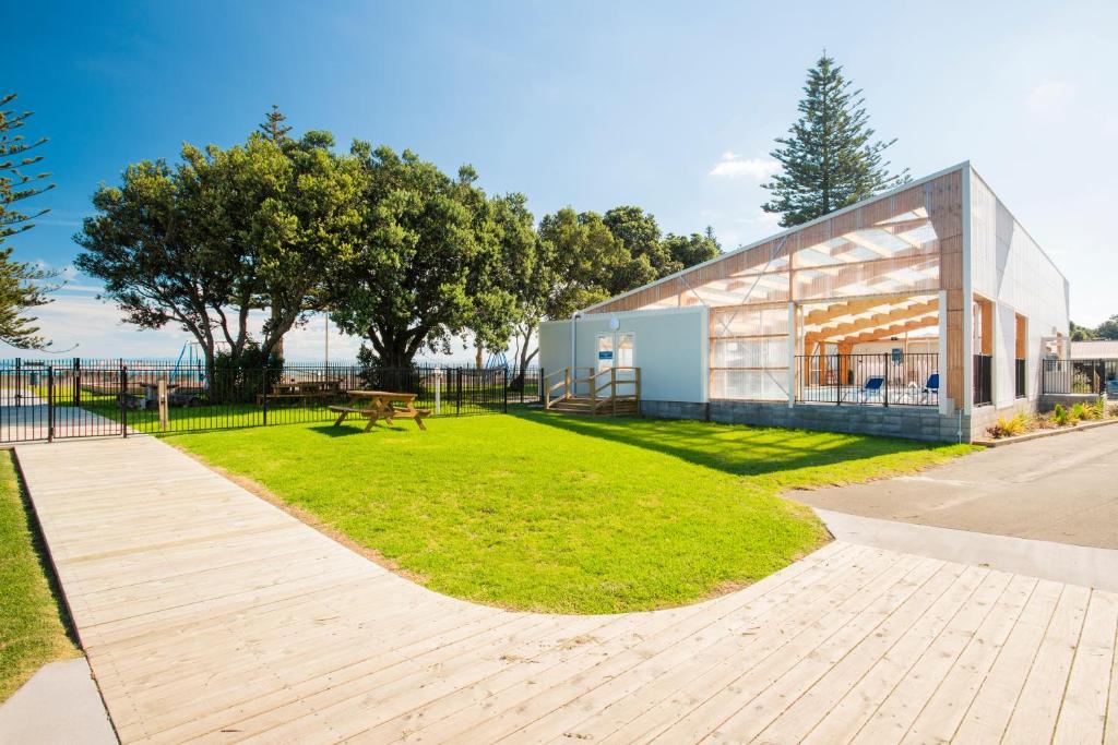 a park with a building and a bench in the grass at Waikanae Beach TOP 10 Holiday Park in Gisborne