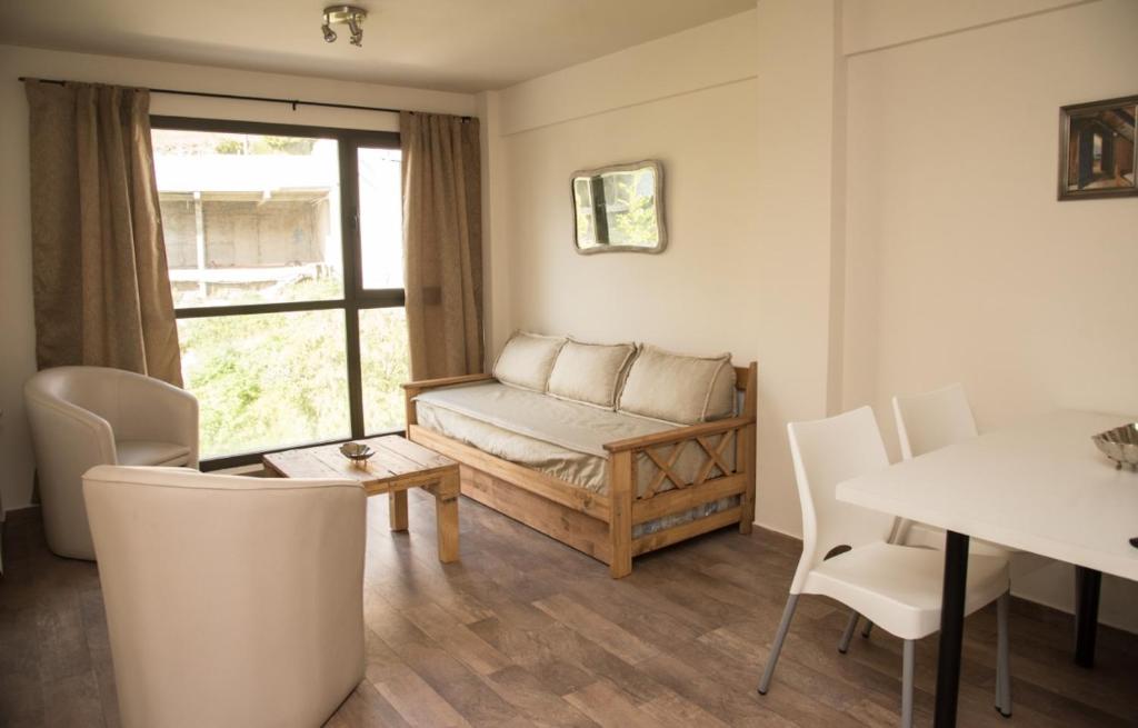 sala de estar con sofá, mesa y sillas en La Bonita Apartment en San Carlos de Bariloche