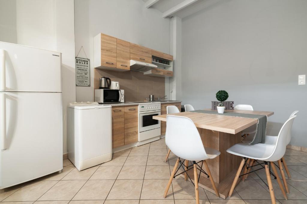 kuchnia z białą lodówką, stołem i krzesłami w obiekcie Spacious apartment-600m from the subway w Atenach