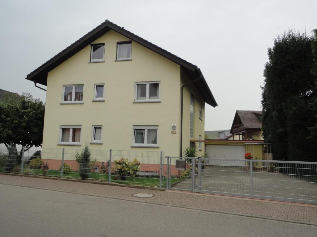 una casa amarilla con techo negro en una calle en Ferienwohnung Toska, en Pfaffenweiler