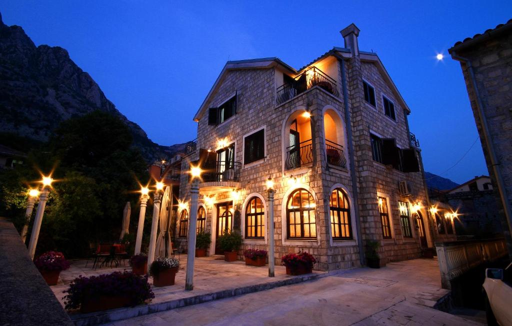 - un bâtiment en pierre avec des lumières allumées la nuit dans l'établissement Panonija, à Kotor