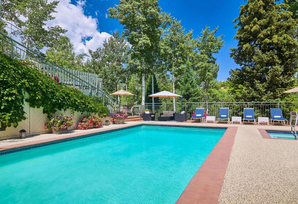 una piscina con sillas y sombrillas en Top of the Village - CoralTree Residence Collection en Snowmass Village