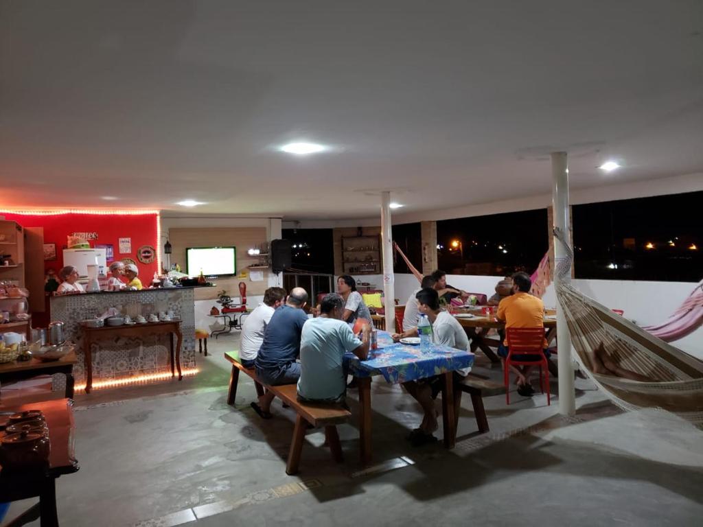 um grupo de pessoas sentadas numa mesa num restaurante em Pousada Voo Livre Tacima em Tacima