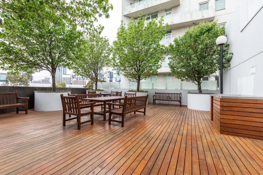 un patio con mesa, sillas y árboles en ☆of Southbank☆Light filled apartment☆HUGE private terrace with city views☆Parking☆Pool☆Gym☆WiFi en Melbourne