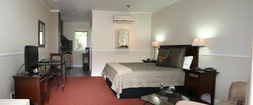 a hotel room with a bed and a living room at Lodge Bordeaux in Whangarei