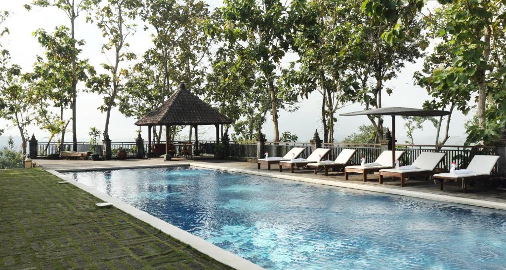 einen Pool mit Liegestühlen und einem Pavillon in der Unterkunft Plataran Borobudur in Borobudur