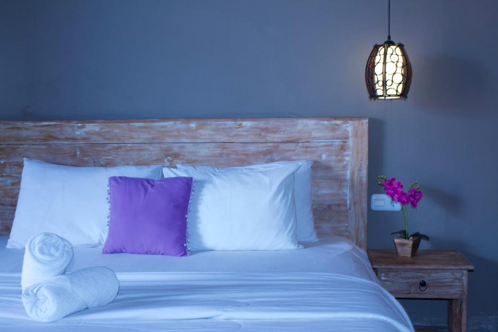 Dormitorio azul con cama blanca y almohadas moradas en Olas homestay bali, en Uluwatu