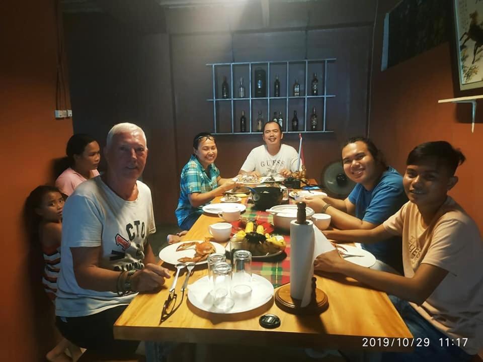 Un groupe de personnes assises autour d'une table à manger dans l'établissement Laguno Bed And Breakfast Hostel, à Moalboal