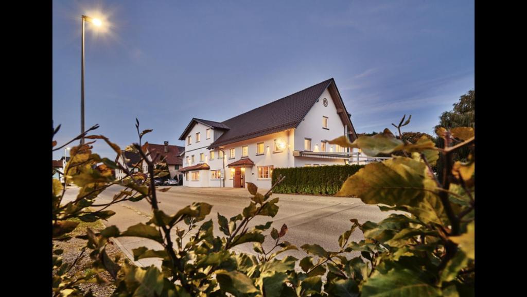 ein weißes Haus mit Straßenbeleuchtung davor in der Unterkunft Landgasthof Löwen in Oberopfingen