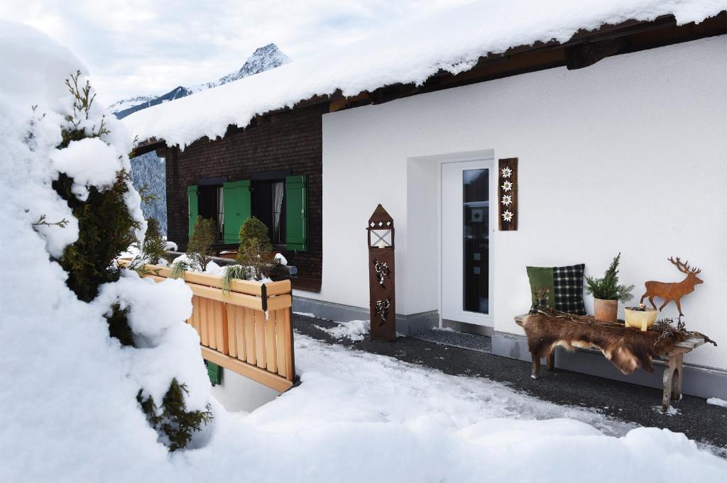 un cerf debout devant une maison dans la neige dans l'établissement Veronikas Chalet, à Sankt Gallenkirch