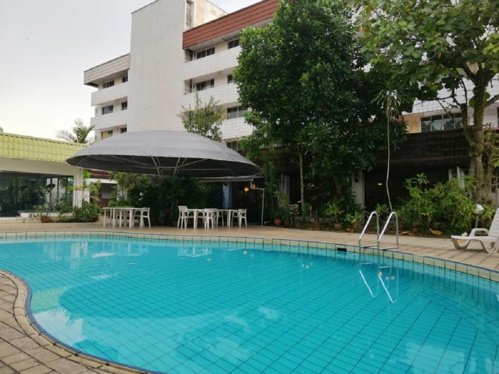 a swimming pool with an umbrella and chairs and a building at Terrace Hotel in Bandar Seri Begawan