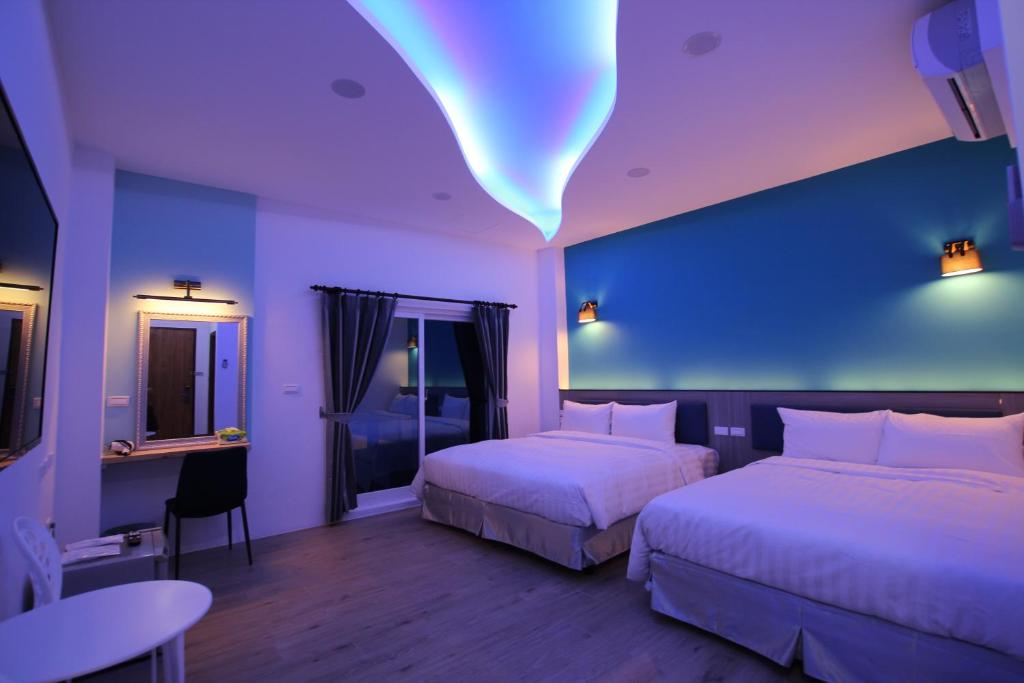 a hotel room with two beds and a blue wall at Lang Qin B&B in Nanwan