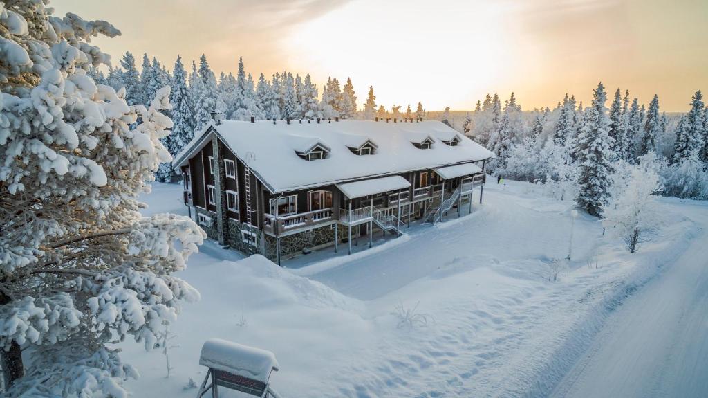 una cabaña de madera en la nieve con árboles nevados en Levi Black Apartments, en Levi