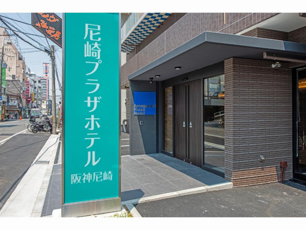 un edificio con una señal verde delante de él en Amagasaki Plaza Hotel Hanshin Amagasaki en Amagasaki