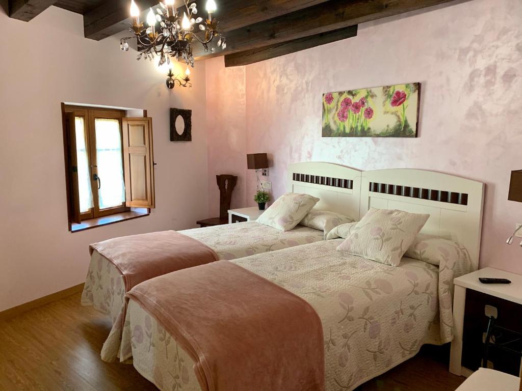 a bedroom with two beds and a chandelier at Villa Fontanas in Hontanas