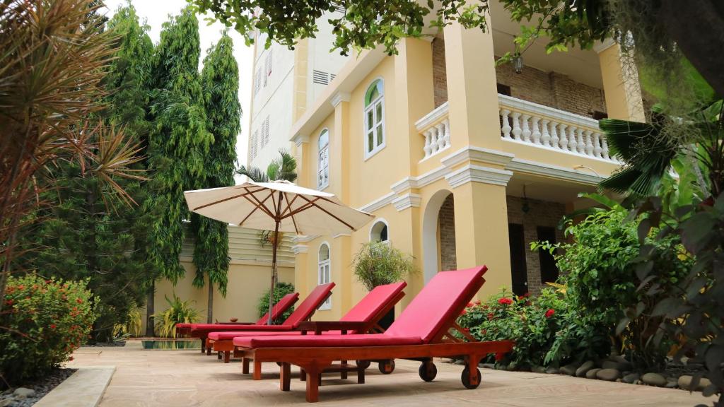 馬德望的住宿－拉維拉酒店，建筑物前的一排椅子和一把伞
