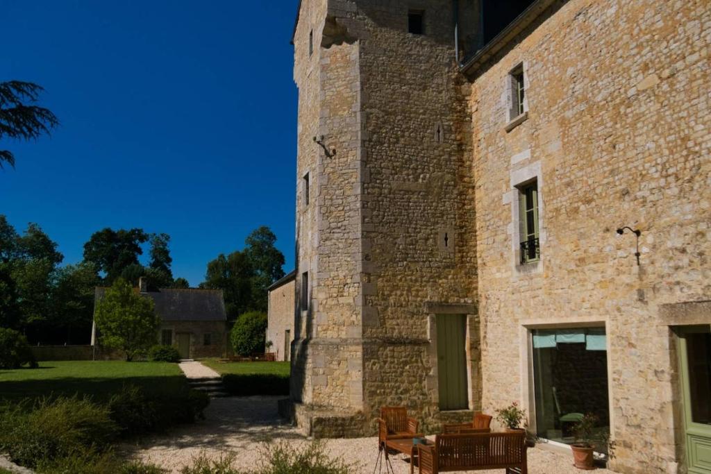 バイユーにあるChâteau de Monceaux 5mn de Bayeux proche Merの大きなレンガ造りの建物で、前に椅子が置かれています。