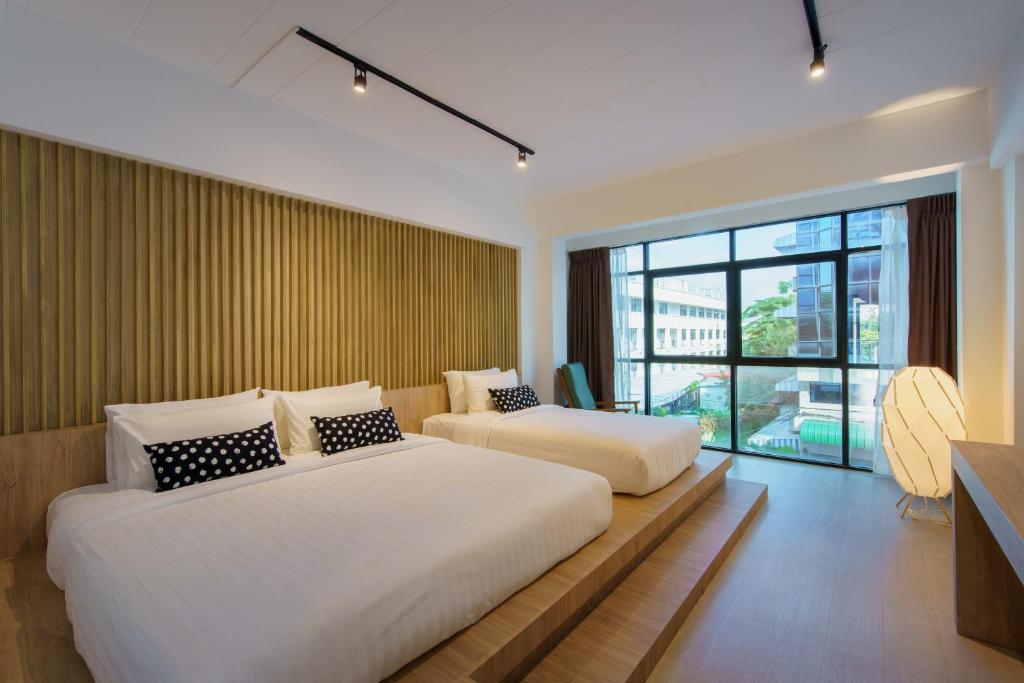 a bedroom with two beds and a large window at Jiang Mai 81 in Chiang Mai