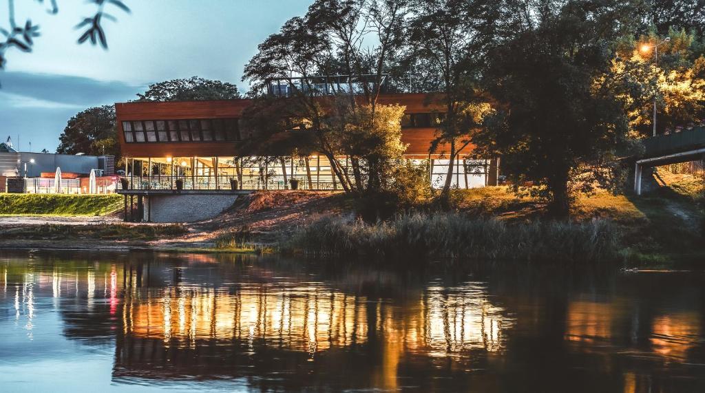 a building on a hill next to a body of water at Hotel Termalny in Uniejow