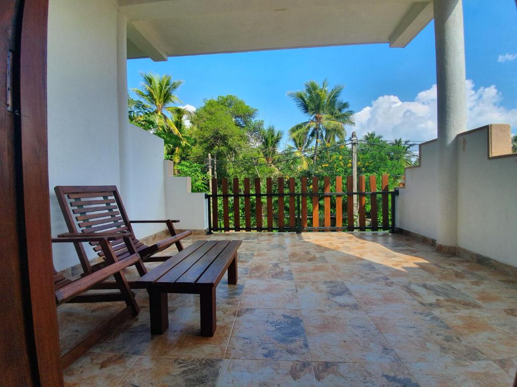 a patio with two chairs and a bench on a balcony at Ambel Homestay in Anuradhapura
