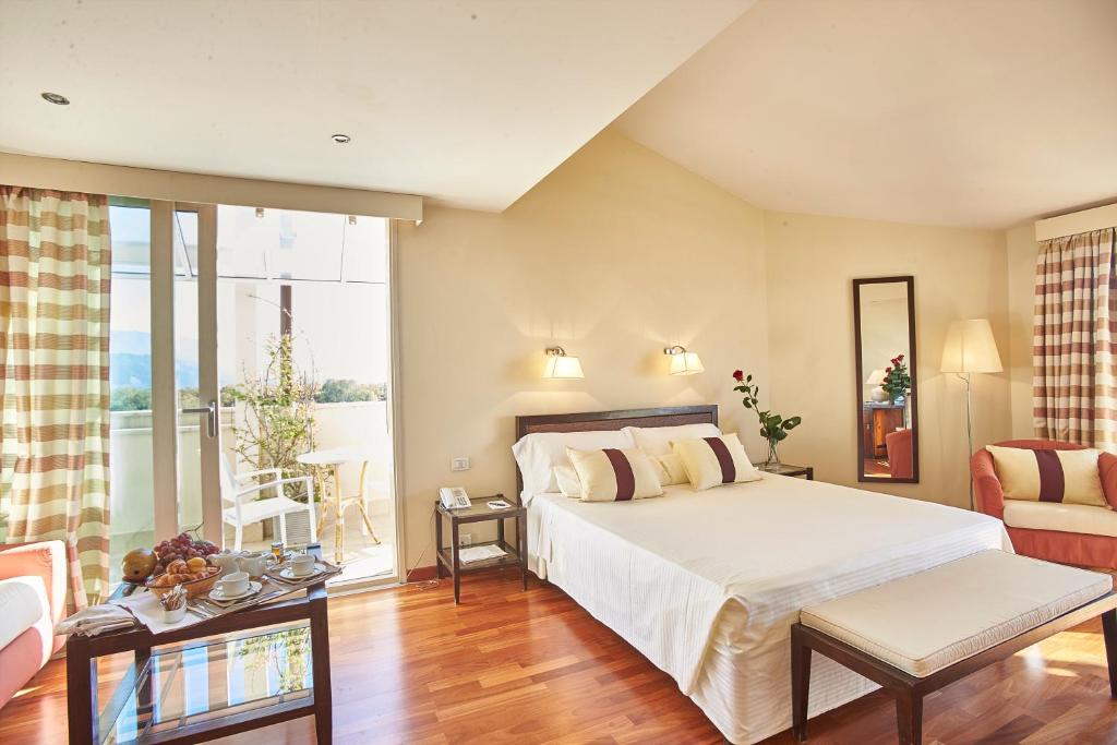a bedroom with a large bed and a living room at Hotel Sina Astor in Viareggio