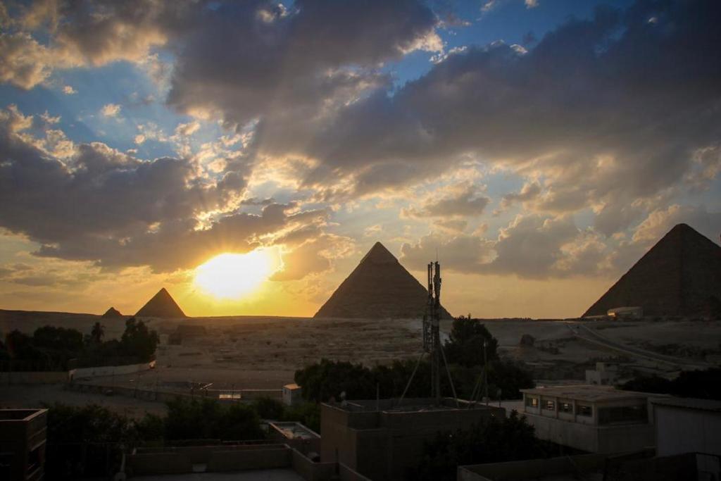 a sunset over the pyramids of giza with the sun setting at Three-Bedroom Apartment at Nazlet El Semman in Cairo