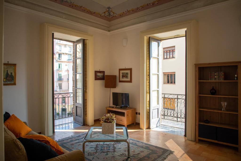 een woonkamer met 2 grote ramen en een bank bij Flavio Gioia Suite Salerno in Salerno
