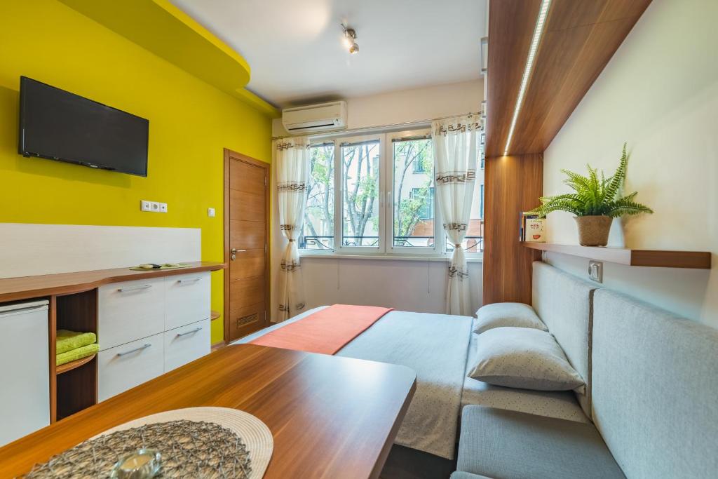Habitación con paredes amarillas, sofá y mesa. en Studio DOLCE VITA en Varna