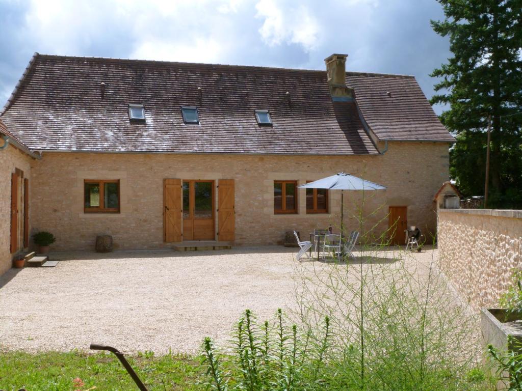 uma casa com um pátio e um guarda-chuva em frente em Maison Périgord Noir près de Lascaux, Montignac, Sarlat, Périgueux em Fleurac