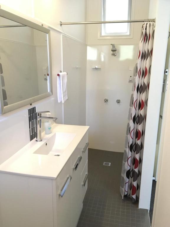 ein Bad mit einem Waschbecken, einem Spiegel und einer Dusche in der Unterkunft Scenic Rim Motel in Aratula