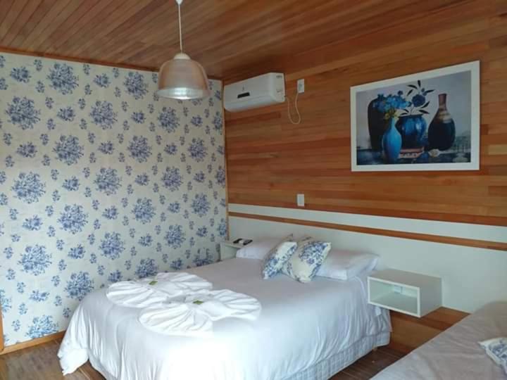 a bedroom with a bed and a picture on the wall at Pousada 3 Irmaos in Urubici