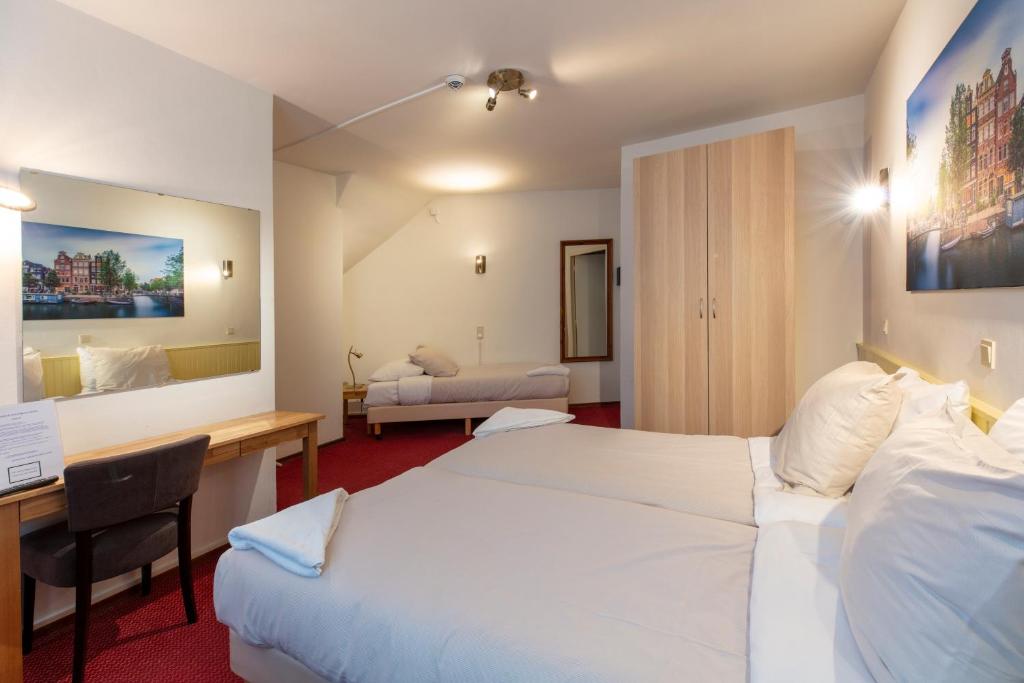 Cette chambre comprend deux lits et un bureau. dans l'établissement Amsterdam Wiechmann Hotel, à Amsterdam