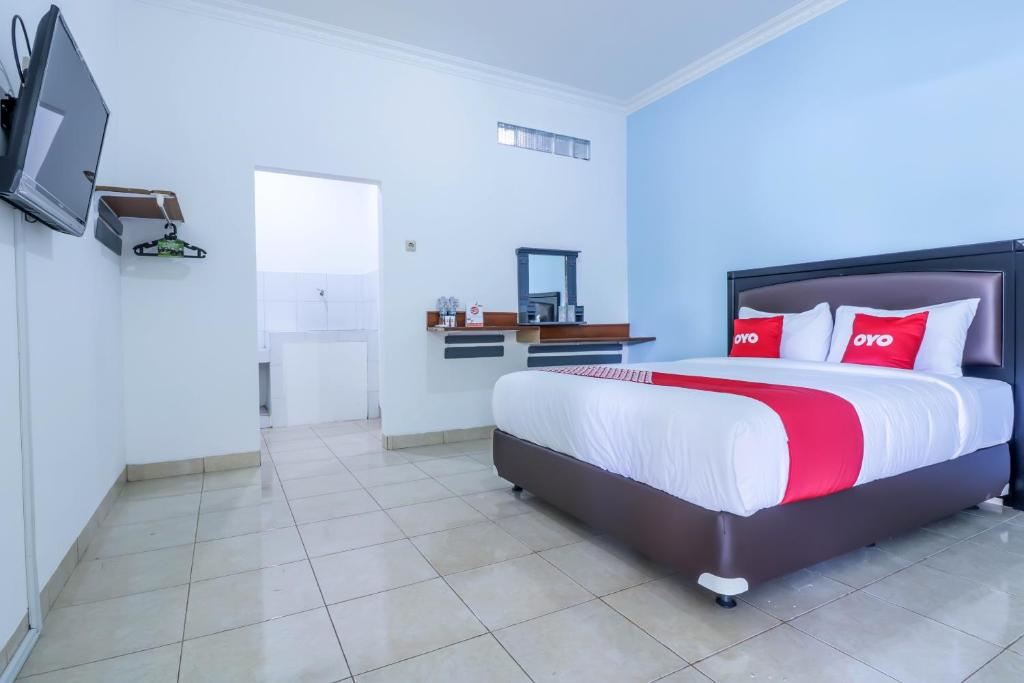 a bedroom with a bed with red pillows and a tv at SUPER OYO 1755 De'balcon Accomodation Near Ngurah Rai Airport in Kuta