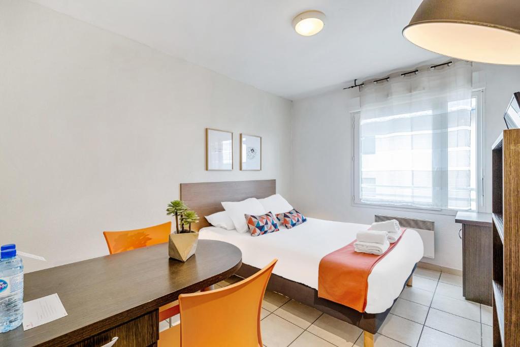 een slaapkamer met een bed en een tafel en stoelen bij Appart'City Classic Thonon Les Bains in Thonon-les-Bains