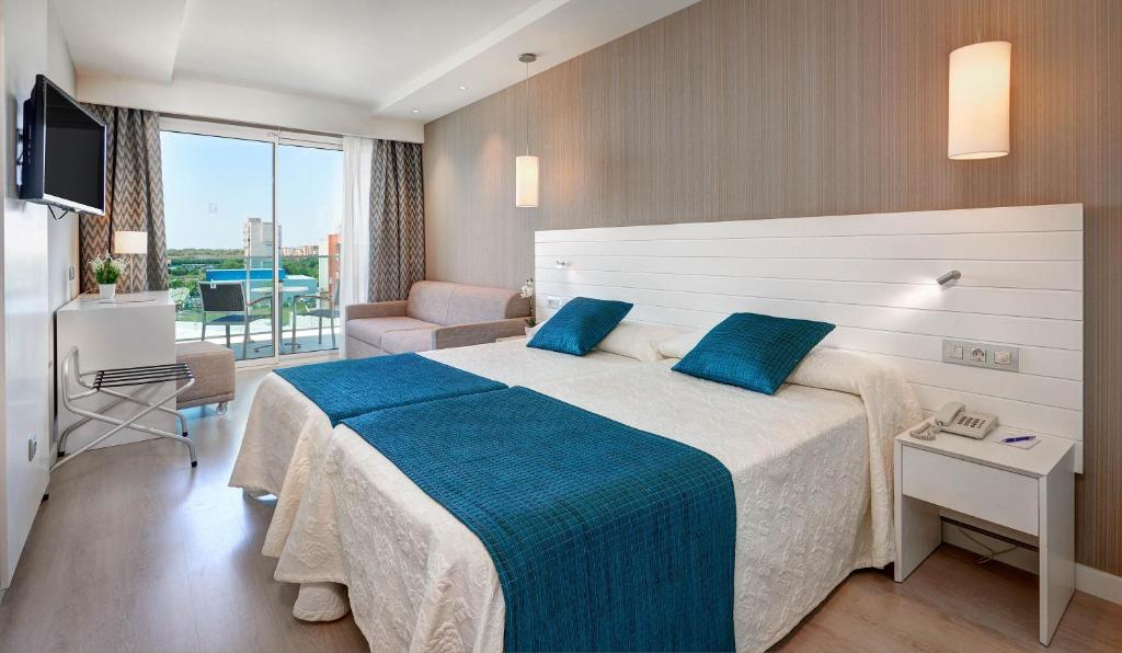 a hotel room with a large bed with blue pillows at Hipotels Said in Cala Millor