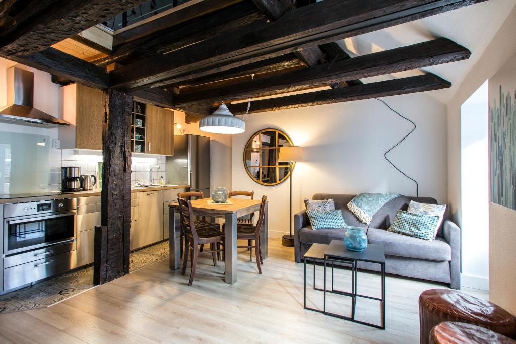 eine Küche und ein Wohnzimmer mit einem Sofa und einem Tisch in der Unterkunft Gîte de l'Ange in Colmar
