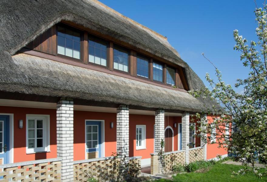 ein rotes Haus mit einem Strohdach in der Unterkunft Fischerhaus Gager in Gager