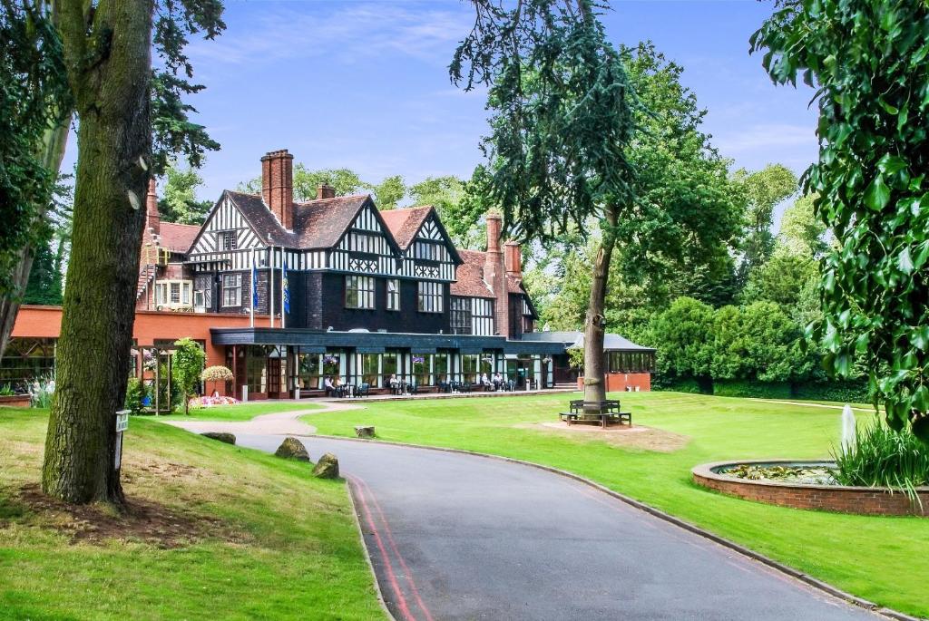 a large black and white house with a driveway at Royal Court Hotel & Spa Coventry in Coventry